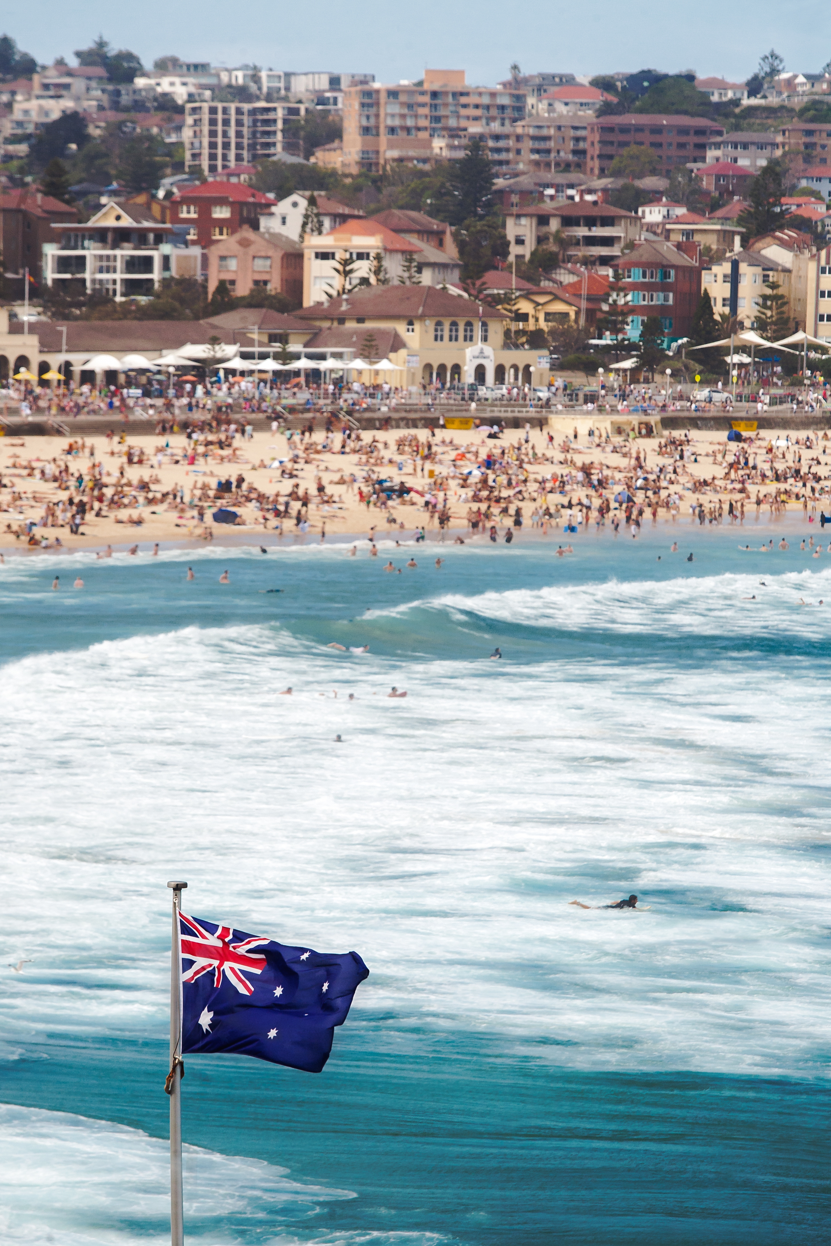 A vertical shot of the Australian flag at the sea in a crowded Bondi beach